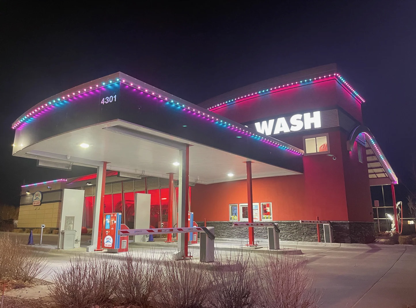 Color-changing permanent LED lighting outlining the canopy and building of a car wash at night